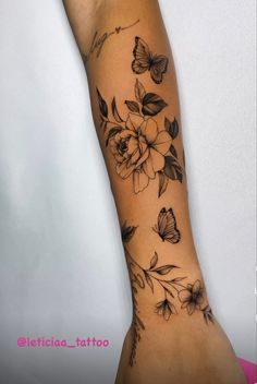 a woman's arm with flowers and butterflies tattooed on the side of her arm