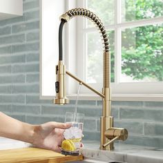 a person is holding a glass in front of a faucet