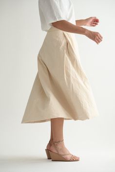 Casey Casey Moon Skirt in Ecru. Pleated skirt in washed cotton with a tailored waist and back button and zip closure. Front pleats hide pockets, while the back pleat creates volume. Lined in cotton. 99% cotton, 1% polyester, 100% cotton lining. Made in France. XS - 27" waist, 33" lengthS - 28" waist, 34" length Pleated Cotton Midi Skirt, Asymmetrical Cotton Skirt In Beige, Asymmetrical Cotton Skirt With Pockets, Beige Cotton Asymmetrical Skirt, Chic Cotton Gathered Skirt Bottoms, Chic Cotton Gathered Skirt, Beige Asymmetrical Cotton Skirt, Beige Pleated Asymmetrical Skirt, Cotton Midi Skirt With Pleated Hem