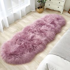 a pink rug is laying on the floor in front of a white dresser and bed