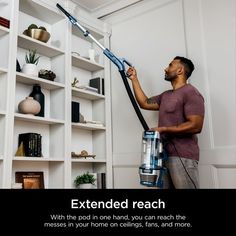 a man is using a vacuum to clean bookshelves