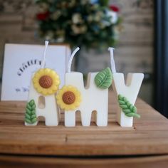 three candles with flowers and leaves on them sitting on a table next to a greeting card