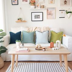 a living room with white couches and colorful pillows on the sofa, along with various framed pictures