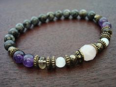 "women's amethyst spiritual balancing mala bracelet made from fair trade amethyst, moonstone, pale pink rose quartz, pyrite, smoky quartz, and grade aa+ black moonstone. amethyst is a stone of spirituality and contentment that represents principles of complete metamorphosis. it is known as a stone of meditation and peace, and balances the energies of the intellectual and spiritual bodies. it opens and activates the third eye and crown chakras, and enhances serenity, spiritual insights, stability Bohemian Amethyst Crystal Bracelet For Meditation, Amethyst Beaded Bracelet For Meditation, Spiritual Lavender Crystal Bracelet For Meditation, Aquarius Bracelet, February Aquarius, Pale Pink Roses, Black Labradorite, Black Moonstone, Pink Rose Quartz