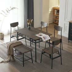 a dining table with four chairs and a magazine on the floor in front of it