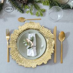 a place setting with gold plates and silverware, pine cones, greenery and napkins