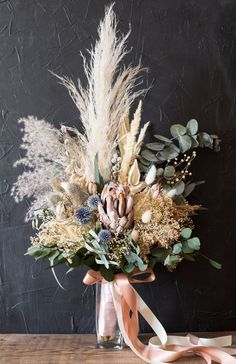 a vase filled with lots of flowers on top of a wooden table next to a ribbon