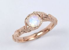 a gold ring with a white opal in the center and leaves on it's sides