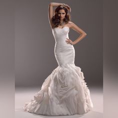 a woman in a white wedding dress posing for a photo with her arms behind her head