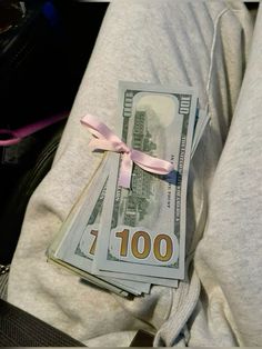 the money is wrapped in pink ribbon and tied with a bow on someone's stomach