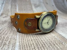 Here's a wide yellow and brown handcrafted steampunk watch.  It is 1-1/2 inches wide and will fit medium to large wrists from 7.0 to 8-3/4 inches around.  Runs on battery. The body of the watchband was hand dyed mustard yellow, and the tabs were hand dyed brown.  The watch band is tapered so your wrist can bend freely.   Antique Brass colored gears, grommets, rivets, and buckle. We also have wide band watches for smaller wrists and narrow width watches in both small and large sizes. Back to shop:  https://www.etsy.com/shop/MonardaZ?ref=hdr-shop-menu Vintage Handmade Adjustable Watch Bands, Vintage Handmade Adjustable Watch Accessories, Handmade Adjustable Brown Watch, Handmade Brown Adjustable Watch, Vintage Brown Cuff Bracelet, Vintage Adjustable Cuff Watch, Vintage Cuff Watch Band As Gift, Vintage Brown Analog Watch Accessories, Adjustable Brown Steampunk Watch Accessories