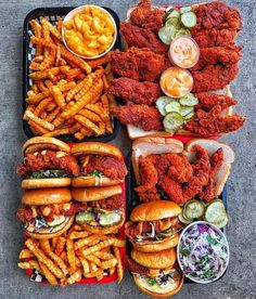 several trays filled with different types of food including chicken, fries and coleslaw