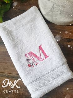 a white towel with the letter m on it sitting next to a potted plant