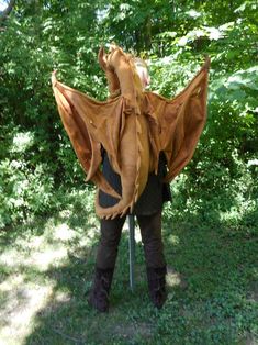 a woman wearing a dragon costume standing in the grass with her back to the camera