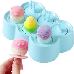 a hand holding an ice cream molder with three pops in it and one on the other side