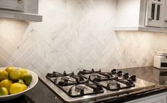 a bowl of fruit sitting on top of a stove in a kitchen next to an oven