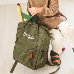 a young boy sitting on the floor with a backpack and pencils in his hand