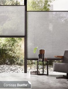 a chair and table in front of a window with blinds on the windowsills