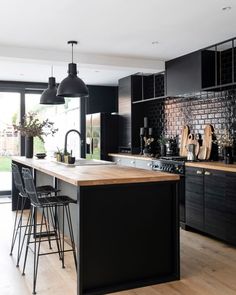 a kitchen with black cabinets and wooden counter tops