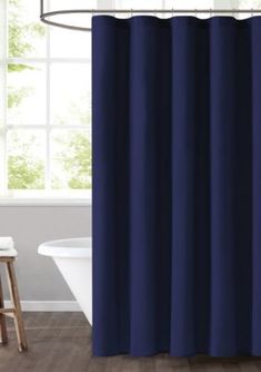 a blue shower curtain hanging in front of a white bathtub and wooden flooring