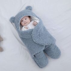 a baby in a blue elephant costume laying next to a teddy bear