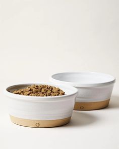 two bowls filled with food sitting on top of a white table next to each other