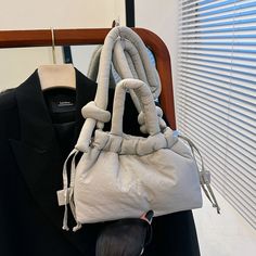 a handbag hanging from the back of a suit jacket on a coat hanger