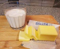 a glass of milk and some cheese on a cutting board