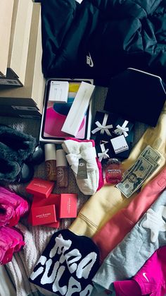 the contents of a purse are laid out on a bed with clothes and other items