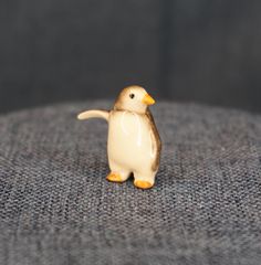 a small penguin figurine sitting on top of a couch