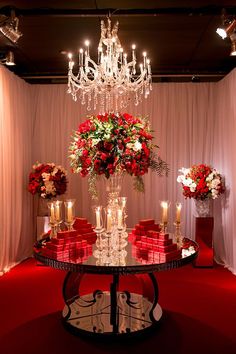 a table topped with lots of red and white flowers next to a chandelier