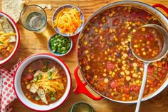 several bowls of chili and corn soup on a wooden table