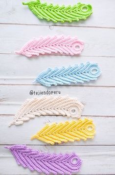 four crocheted leaves sitting on top of a wooden table next to each other