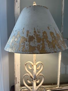 a lamp that is sitting on top of a table in front of a window with peeling paint