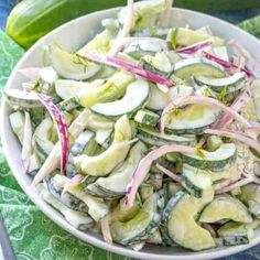 a white bowl filled with sliced vegetables on top of a green and blue table cloth