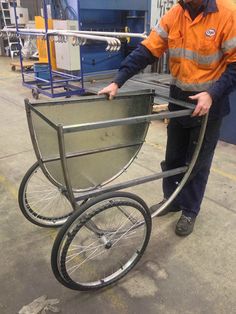 a man in an orange jacket pushing a metal cart