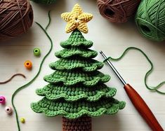 a crocheted christmas tree sitting on top of a table next to balls of yarn