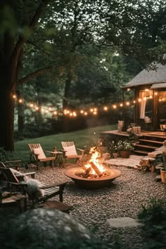 an outdoor fire pit surrounded by chairs and lights