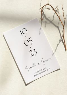 a wedding card with the date printed on it next to a twig and dried plant