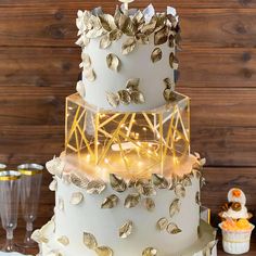 a three tiered white cake with gold decorations