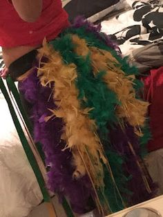 a woman in a red shirt is sitting on a chair with feathers around her legs