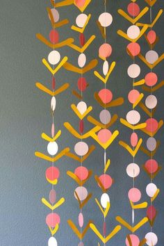 a mobile made out of paper and colored circles hanging from it's sides on a wall