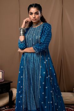 Blue anarkali in bandhani print with mirror and thread embroidery on the yoke. Paired with off-white cotton silk pant.
Component: 2
Pattern: Printed
Type Of Work: Bandhani
Neckline: Round
Sleeve Type: Straight Three Quarter
Fabric: Cotton Silk
Color: Blue
Other Details: 
Cutwork hem anarkali and pant
Occasion: Puja - Aza Fashions Festival Chanderi Palazzo Set With Bandhani Print, Designer Bandhani Print Kurta With Traditional Drape, Blue Bandhani Print Chanderi Salwar Kameez, Designer Wear Kurta With Bandhani Print And Traditional Drape, Blue Bandhani Chanderi Salwar Kameez, Designer Bandhani Print Palazzo Set For Navratri, Floor-length Bandhani Print Kurta For Festive Occasions, Festive Bandhani Print Churidar For Transitional Season, Transitional Designer Anarkali Set With Bandhani Print