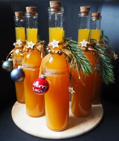 six bottles filled with orange liquid on top of a wooden tray next to christmas decorations