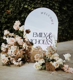 a welcome sign with flowers on the ground next to it and a bouquet of flowers