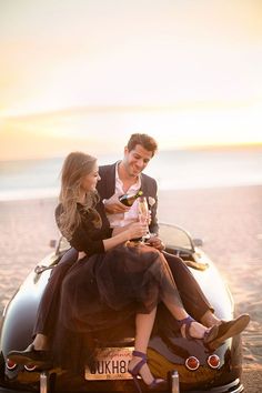 two people sitting on the back of a car