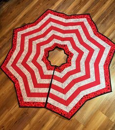 an open red and white striped umbrella on the floor with wood floors in the background