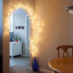 a room with a table, chair and archway decorated with lights