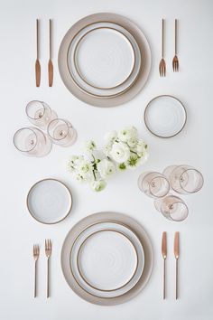 the table is set with plates, silverware and flowers