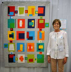 a woman standing next to a colorful quilt